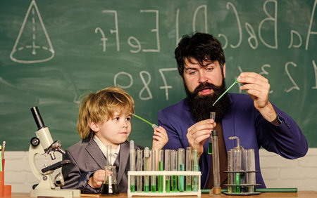 bearded man teacher with little boy. father and son child at school. Laboratory test tubes and...