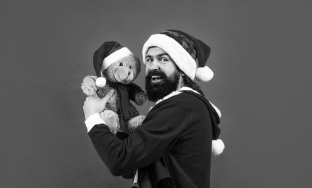 happy bearded man with teddy bear toy in santa claus costume celebrate winter holiday of chistmas and feel merry about xmas gifts, christmas shoppingの写真素材
