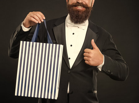 happy man in tuxedo bow tie with shopping bag. shopping sale. copy space. thumb up.の写真素材