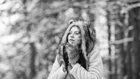 Girl in snowy forest. Faux fur animal hat perfect for fantasy theme. Heartwarming concept. Animal care. Winter themed portrait cosy outfit. Woman wear wolf hat. Animal rights. Wild life symbolの写真素材