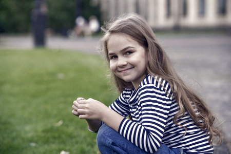 Lets your child have cared better. Happy child sit on haunches outdoors. Little girl child in casual style. Fashion trend. Trendy style. Childcare and childhood. International childrens dayの写真素材