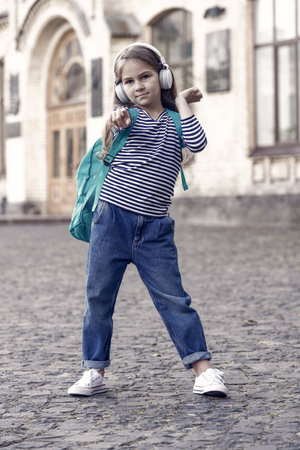 Adventure is out there. Little traveler point finger ahead. Small kid listen to music wearing backpack. Childhood adventure. Adventure holiday. Vacation trip. Traveling and wanderlust. Free your mindの写真素材