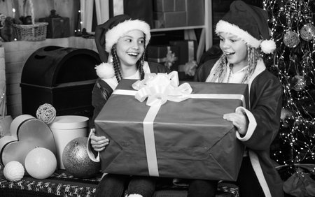 Winter masquerade. Happiness and joy. Santa crew. Girls friends sisters Santa claus costumes received gift. Santa party. Happy new year. Children having fun on christmas eve. Giant enormous surpriseの写真素材