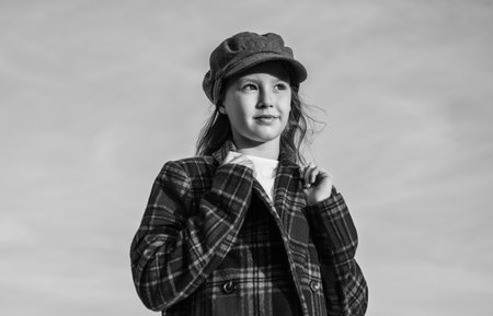 teen girl wear trendy hat and checkered jacket looking far away on sky, kid fashionの写真素材