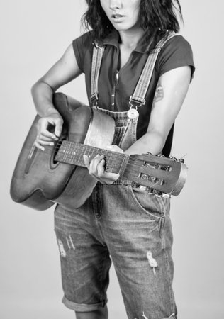 musical shop. country music style. attractive beauty with acoustic guitar. musical string instrument. female singer sing a song. happy woman play the guitar. girl guitarist in shirt and jeansの写真素材