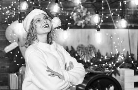 Happy christmas eve. Girl adorable smiling face Santa claus hat enjoy season. Festive decorations and accessories. Festive mood concept. Do something exciting and crazy to remember the festive withの写真素材