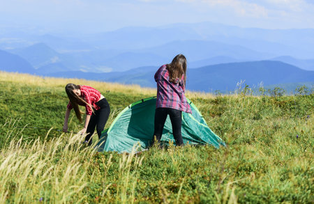 Ready to get refreshed. family camping. reach destination place. hiking outdoor adventure. two girls pitch tent. wanderlust discovery. mountain tourism camp. friends spend free time togetherの写真素材
