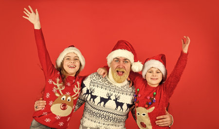 Merry Christmas. dad embrace daughters. bearded santa man with kids. knitted fashion for everyone. warm and cosy winter. new year is coming. happy family celebrate xmas. small girls love their fatherの写真素材
