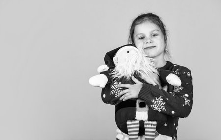 Christmas vibes concept. Christmas traditions. Dear Santa. Small kid carry Santa toy blue background. Little girl toy present. Winter holidays. Gift brings joy and happiness. Merry christmasの写真素材
