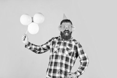 mature guy in checkered shirt with party balloons. stylish male having fun on birthday. bearded man celebrate holiday. anniversary. surprise for him. event manager with giftの写真素材