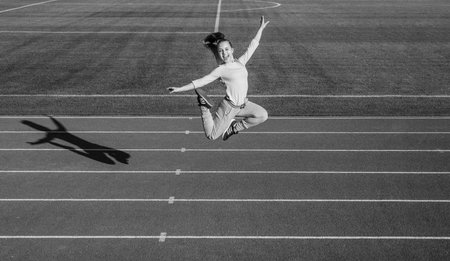 Happy energetic girl child jump on running track, athleticsの写真素材