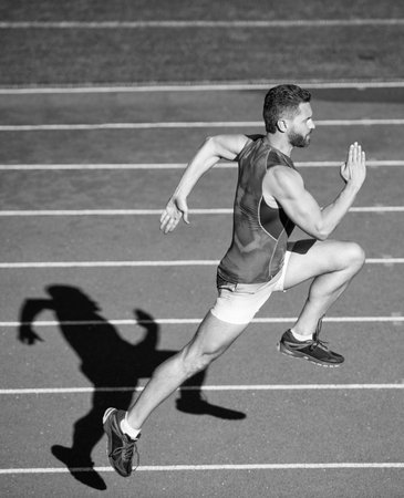 energetic athletic muscular man runner running on racetrack at outdoor stadium, enduranceの写真素材