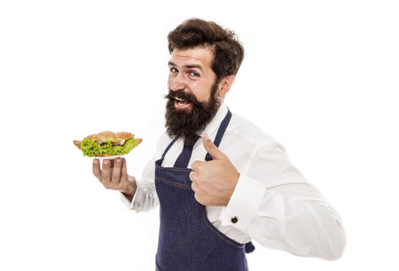 Delicious croissant. Cafe concept. Guy serving croissant stuffed with lettuce and fresh vegetables. Healthy food. Chef proud of croissant meal. Man bearded waiter wear apron carry plate with dishの写真素材