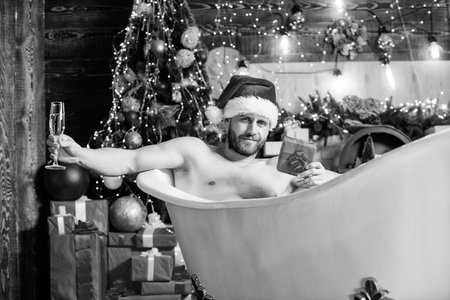Playfully sexy. muscular man relax bathtub. best xmas present. christmas spa. sexy mature man bath. winter holidays. happy new year gift. erotic wish. feel desire. macho drink champagne after partyの写真素材