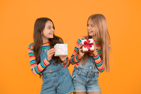 Teaching kids be thankful. Children hold gift boxes yellow background. Kids delighted gifts. Girls celebrate holiday. Thankful for every gift of fate. Happy friends. Being thankful for everythingの写真素材