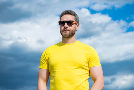 man in yellow shirt and sunglasses outdoor on sky backgroundの写真素材