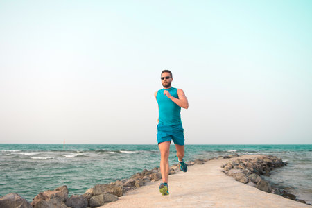 man in sportswear running on sea coast. future success. successful runner. summer activity. sport recreation. healthy lifestyle. run for success. Towards success. practices sport running for lifeの写真素材