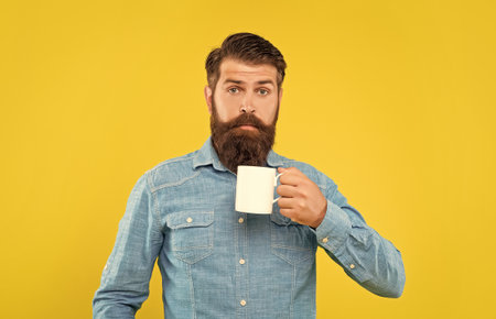 Surprised man holding tea mug yellow background, surpriseの写真素材