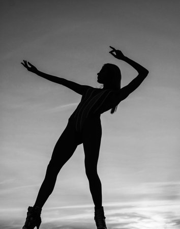 female silhouette on sunset sky background of dancing woman, silhouetteの写真素材