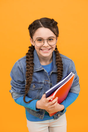Happy kid with nerd look hold school books in casual fashion style yellow background, back to schoolの写真素材