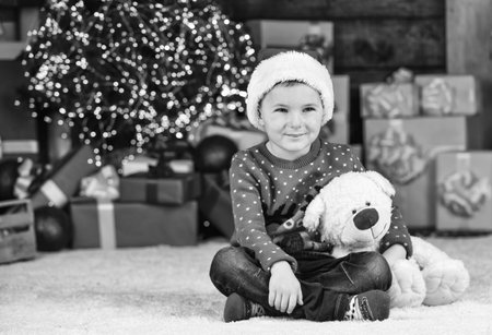 Portrait kid with gift. toy shop open at xmas. merry christmas. happy new year. happy child santa hat. son ready to celebrate winter holidays. small boy excited with present. kid hold bear toy giftの写真素材