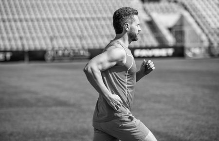 athletic muscular man running in sportswear on stadium track, enduranceの写真素材