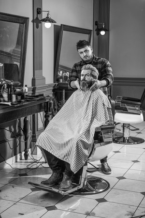 Time for new haircut. hipster man with beard cutting his hair in a barbershop. Professional hairdressing work. Lifestyle. master barber does the hairstyle and styling with dryer. Concept Barbershopの写真素材