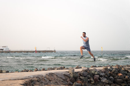 athlete runner along sea coast. running to success. summer vacation. copy space. speed concept. goal and future. people and nature. man runner focused on achievement. life as marathon or sprintの写真素材