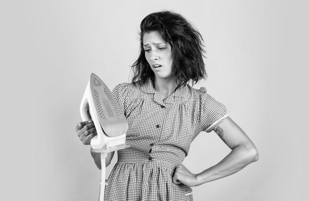 cant live without it. unhappy housekeeper ironing. concept of householding. steaming iron. pinup girl prepare ironing. lady hold modern iron. Everyday life and housework. retro woman with ironの写真素材
