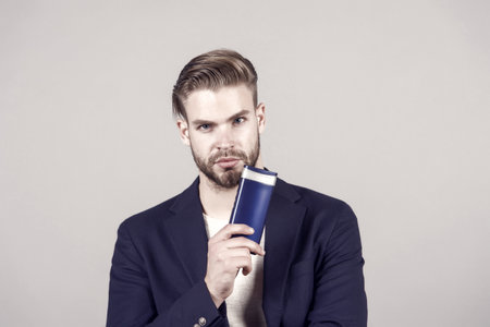 Remedies get rid of dandruff. Man formal suit hold bottle shampoo grey background. Itchy scalp and flakiness skin. Shampoo solve dandruff problem. Dandruff common male problem. Anti dandruff shampooの写真素材