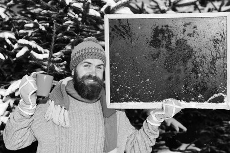 Macho with beard holds cup and blackboard with frost onの写真素材