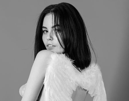 Lady sexi dressed as angel, red background, rear view. Girl naked, tender and pure, innocent. Angel sexy girl with fluffy feather wings. Sexy angel concept. Woman on mysterious face play role gameの写真素材