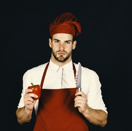 Chef holds knife and tomato on black backgroundの写真素材