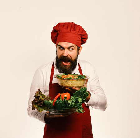 Chef holds bowl with potato casserole and vegetables.の写真素材