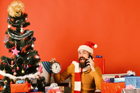 Santa Claus talks on mobile phone near tree