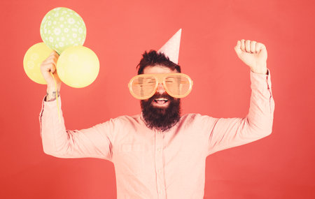 Hipster in giant sunglasses celebrating birthday. Guy in party hat celebrates holiday. Celebration...