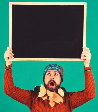 Hipster with surprised face and beard with autumn leavesの写真素材