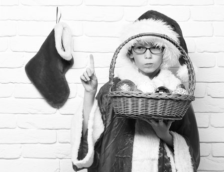 small baby boy with adorable curious face in yellow sweater laying on tummy with christmas or xmas stocking or boot on white brick wall backgrounの写真素材