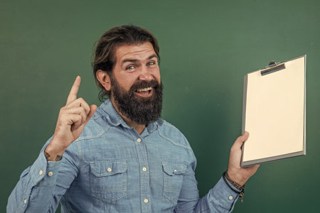 idea. knowledge day. mature bearded teacher with document folder. brutal man work in classroom with blackboard. prepare for exam. college lecturer on lesson. back to school. formal educationの写真素材