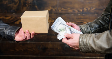 Cash money and box with forbidden goods exchange. Illegal deal concept. Money cash in hand of...