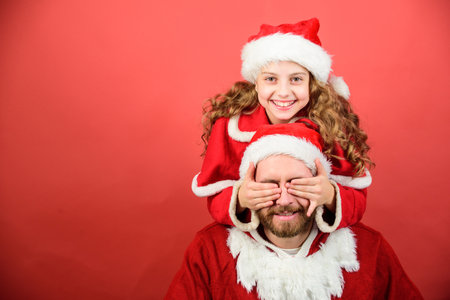 Belief in santa constitutes most magical part of childhood. Guess who. Surprise concept. Girl child and bearded father wear santa costume. How to be santa claus parents guide. My dad is santa clausの写真素材