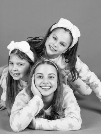 Happy children lying close on each other pink background. Happy childhood portrait in pajamas