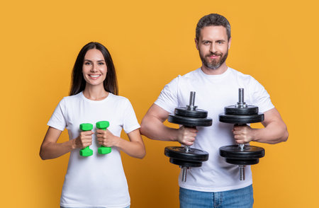happy sport couple with dumbbell isolated on yellow background. sport coupleの写真素材