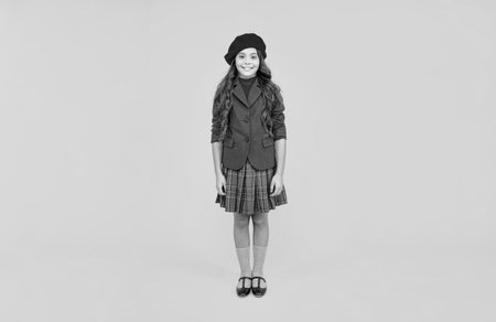 happy teen girl in uniform and beret on yellow background, fashionの写真素材