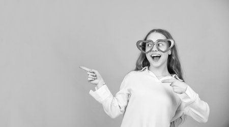 amazed kid in party glasses pointing finger on blue background with copy space, fashion accessoryの写真素材