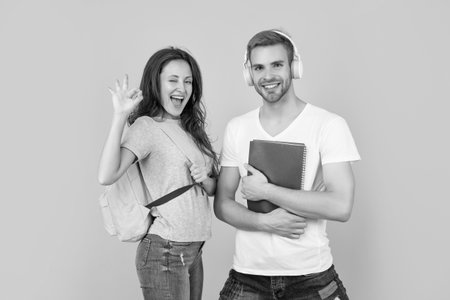 university students on yellow background. study with workbook. ok. glad coupleの写真素材