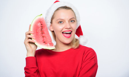 Woman santa hat hold slice watermelon. Prolong summer. Travel christmas vacation and holidays resort. Delicious christmas concept. Christmas summer destinations. Christmas girl eat watermelonの写真素材