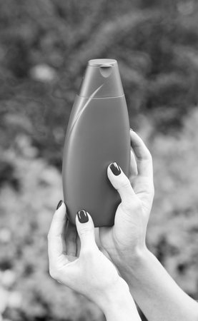presenting cosmetic product. hand hold unbranded shampoo advertisement.の写真素材