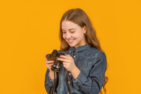 Happy teen girl photographer looking at camera screen yellow background, photographingの写真素材