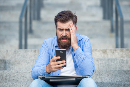 Disappointed guy lost bet. Upset guy checking up betting results in mobile phone. Making bet